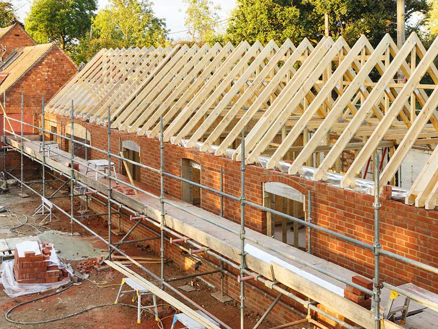 A picture of a red brick house being built with scaffolding attached