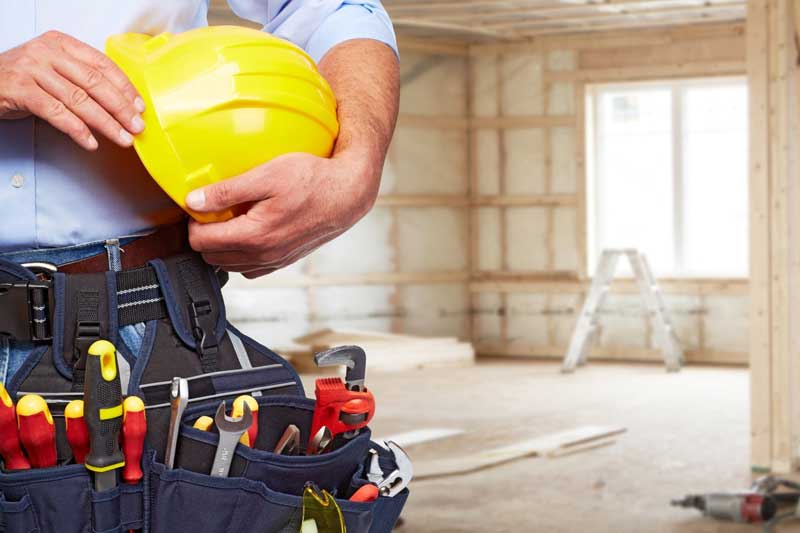 A picture of a builder holding yellow safety helmet on a building site